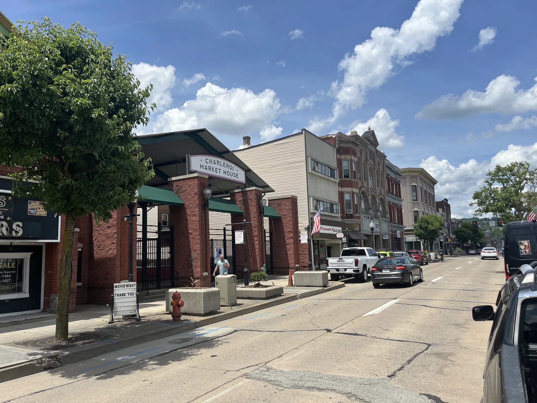 A street features old buildings next to a new brick complex called the Charleroi market house.