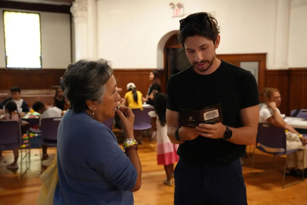Man reads from booklet to older woman.