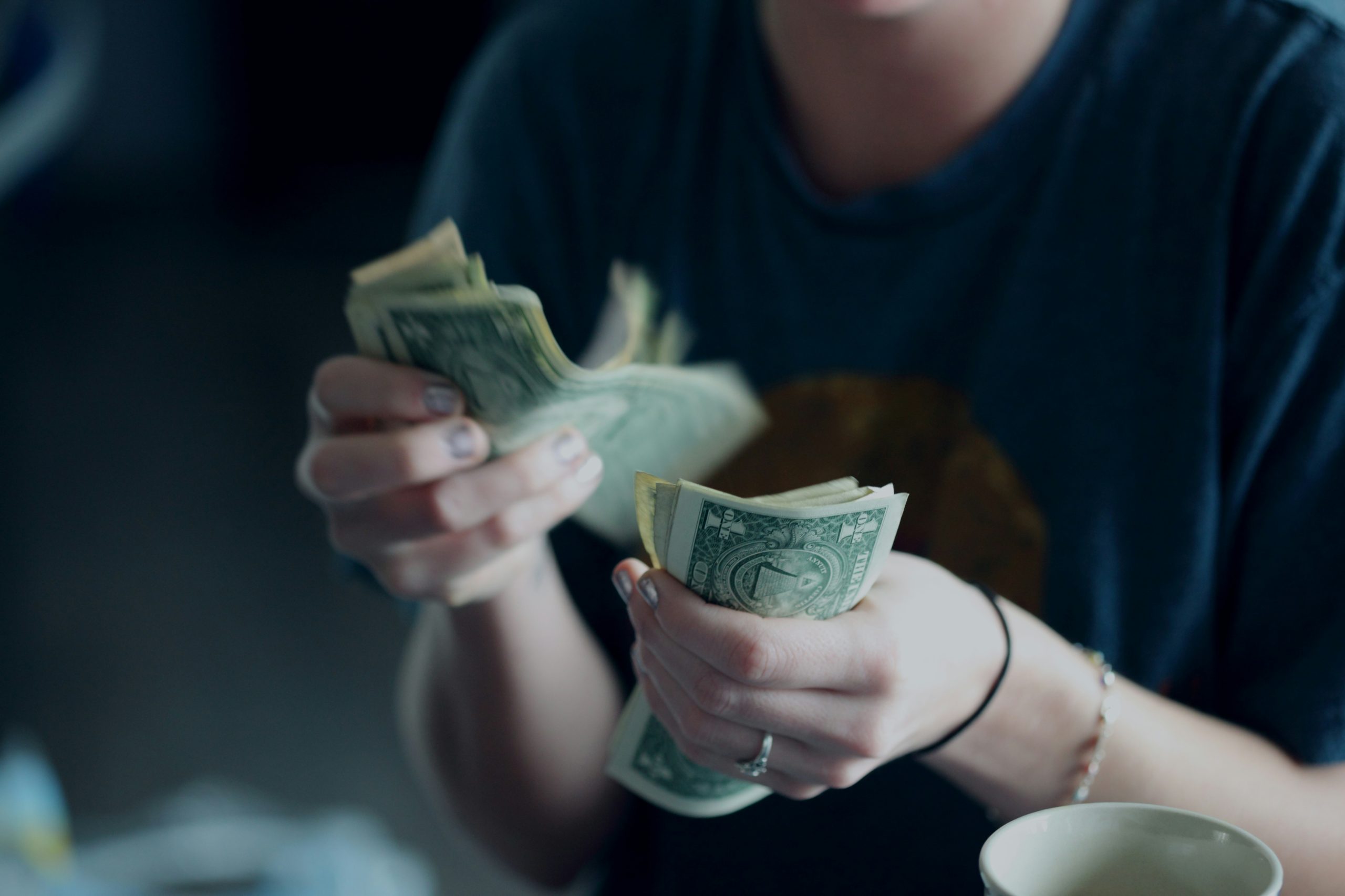 The hands of a person counting dollar bills.